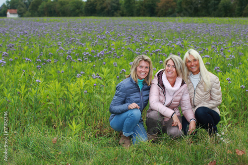 Photographie Three happy mature woman sitting in the meadow
