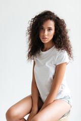 Sticker - Beautiful young woman with curly hair posing while sitting