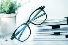 Close Up Black Reading Eyeglasses On The  Stacking Of Office Paper , Business Working Document And Information Data Concept.