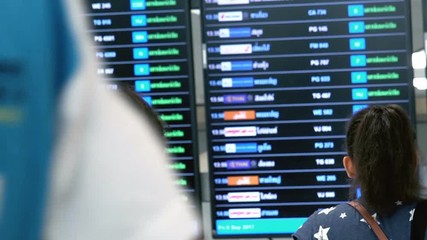 Fototapete - Tourist looking and checking the airport information board for airline flight departure status