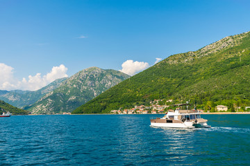 Wall Mural - MONTENEGRO, KAMENARI - JUNE 04/2017: tourists swim in the Boka Kotorska Bay on a motor catamaran.