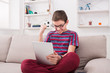 © Prostock-studio - Teenage boy using digital tablet on sofa at home