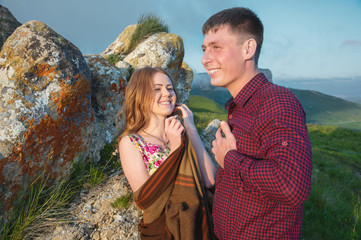 Young married couple laughing happily in nature against the background of rocks and stones