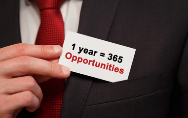 Wall Mural - Businessman putting a card with text 1 year is 365 opportunities in the pocket