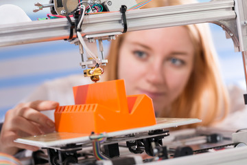 Wall Mural - A female student or laboratory assistant in the automation laboratory is debugging the work of the 3d printer. 3d printer is a device for modeling 3D objects