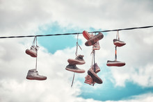 Vintage Stylized Picture Of Old Dirty Shoes Hanging On Wire.