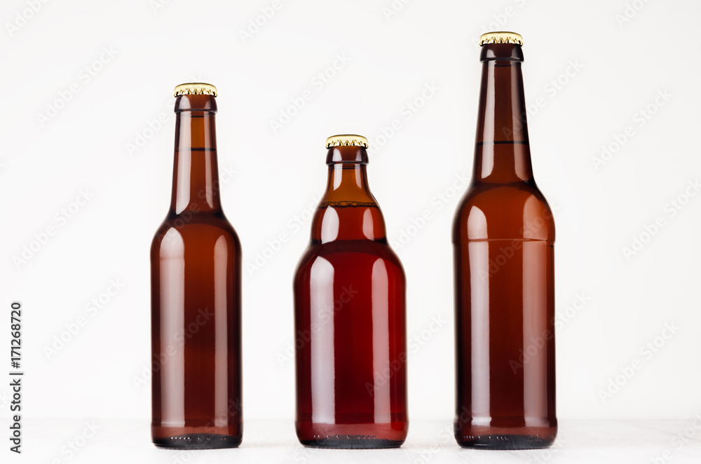 Set of different brown beer bottles  500ml and 330ml mock up. Template for advertising, design, branding identity on white wood table. - obrazy, fototapety, plakaty 