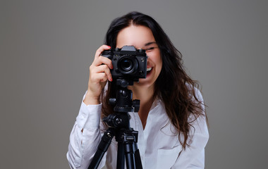 Female holds digital photo camera and a tripod.