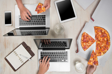 Top view of business people working at office desk and having a lunch break with a tasty pizza