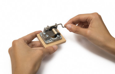 Hands Winding The Mechanism Of A Music Box, Isolated On White Background