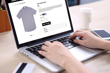 Sticker - People buying casual shirt on ecommerce website with smart phone, credit card and coffee on wooden desk