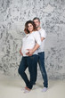 © singulyarra - Young pretty pregnant woman and man in jeans poses in white studio