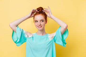 Wall Mural - Smiling ginger woman in dress corrects her hairstail and looking away