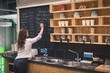 © Wavebreak Media - Female owner writing a menu on black board