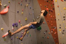 Male Athlete Looking Up While Climbing Wall In Gym