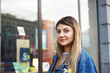 © shurkin_son - Attractive mixed race young woman with long bleached hair, brown eyes and facial piercing, standing on city streets, waiting for friends for a walk, looking at camera with serious expression on face