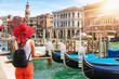 Touristin mit Sonnenhut steht mit einer Landkarte in der Hand am Canale Grande in Venedig, Italien