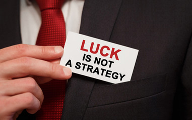Poster - Businessman putting a card with text Luck is not A Strategy in the pocket