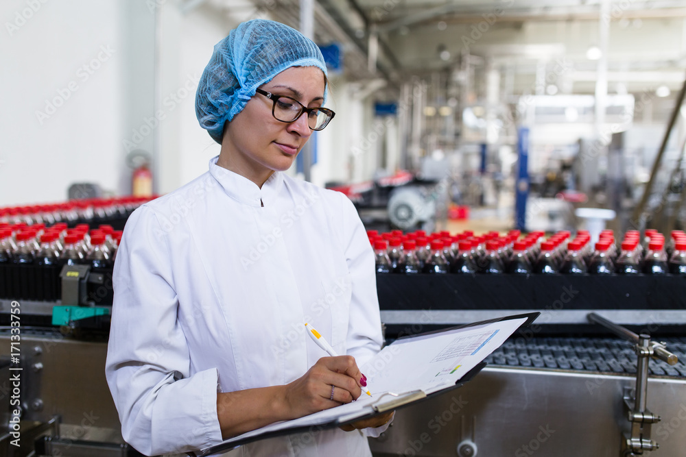 Woman Quality Control Serious middle age woman quality control worker checking robotic line ...