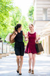 © Kzenon - Two young beautiful women looking for fashion boutiques while carrying paper bags during shopping downtown in summer