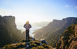 © Jacques van Zyl/Stocksy - A Male hiker standing on a mountain edge admiring the spired mountain valley at sunrise.