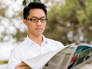 Business man reading a newspaper in park