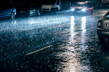 Car In Motion With Switched On Headlights Driving During Heavy Rain