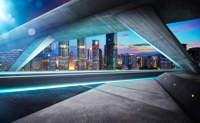 Wall Mural - Empty asphalt road under the bridge during the night with beautiful city skyline background .