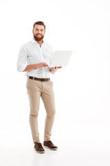 Wall Mural - Happy young bearded man using laptop.