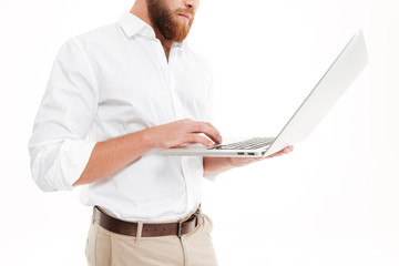 Wall Mural - Cropped photo of handsome young bearded man using laptop.