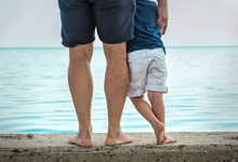 Father And Son Stay On The Sea Beach Under Sunlight At Summer Ti