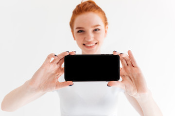 Sticker - Smiling ginger woman showing in front of blank smartphone screen