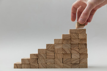 Male hand stacking wooden blocks. Business development and growth concept