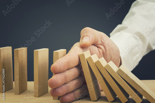 Fotografía Businessman halting the domino effect inserting his hand between falling and upr