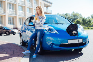 Attractive nice woman waiting for her car to be charged