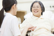 © amanaimages - Nurse touching patient＇s hand in wheelchair