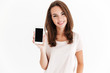 Joyful brunette woman showing blank smartphone screen