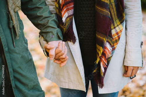 Zdjęcie XXL Szczegół młoda para kochankowie trzyma ręki w jesieni przy parkiem. Romantyczny mężczyzna i kobieta w miłości.