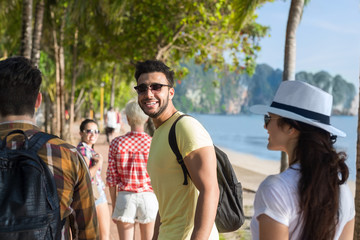 Wall Mural - people group walking in palm tree park on beach talking, casual friends tourists on sea summer vacat