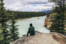 Man Looking At View While Sitting On Cliff At Jasper National Park