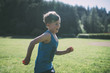 © Cavan Images - Side view of happy boy running with ball at park