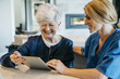 © Cavan Images - Happy senior woman using tablet computer with home caregiver