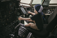 Boy Sitting In Cockpit Of Airplane