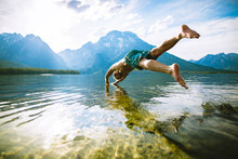 Man Diving Into Lake Against Mountains And Sky