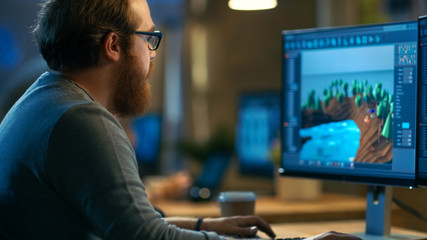 Poster - Male Game Developer Works on a New Level Design. He's Handsome Bearded Man with Glasses and Works in a Creative Office with other Talented People.