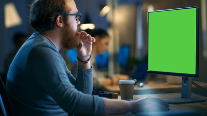 Poster - Creative Bearded Man Works on a Personal Computer with Isolated Mock-up Green Screen. His Office Space is Modern and Cool.