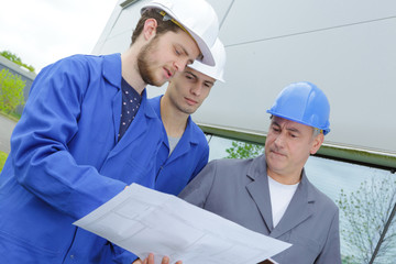 builders on a construction site holding a plan