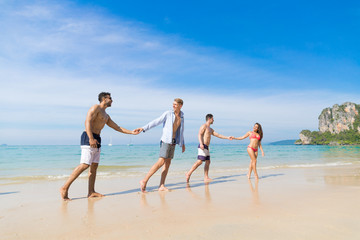 Wall Mural - two couple on beach summer vacation, young people in love walking, man woman holding hands sea ocean