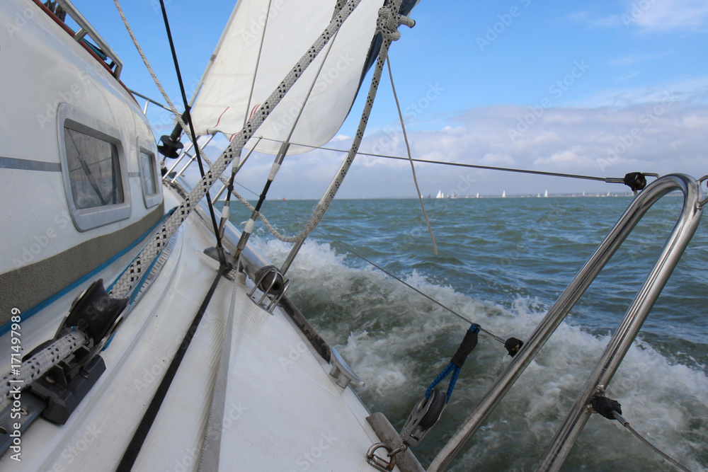 Sail boat gliding in open sea during a race in The Solent near Isle of Wight, England - obrazy, fototapety, plakaty 