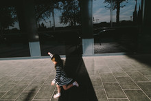 Little Girl Running  Through The Sunbeam Along The Street